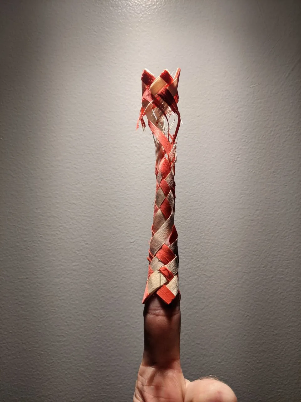 A woven finger trap hanging from a finger.